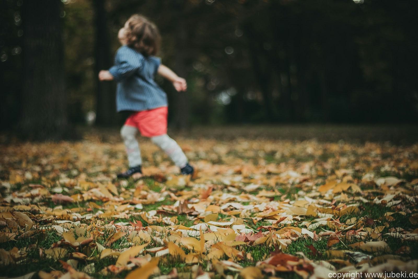 Familie mit Kindern beim Spielen im Herbstlaub