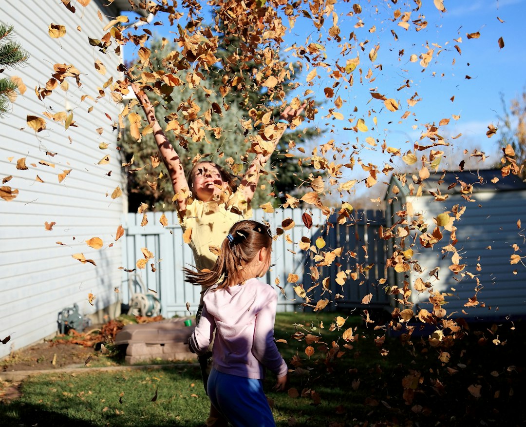 Kinder spielen im Herbst mit buntem Laub