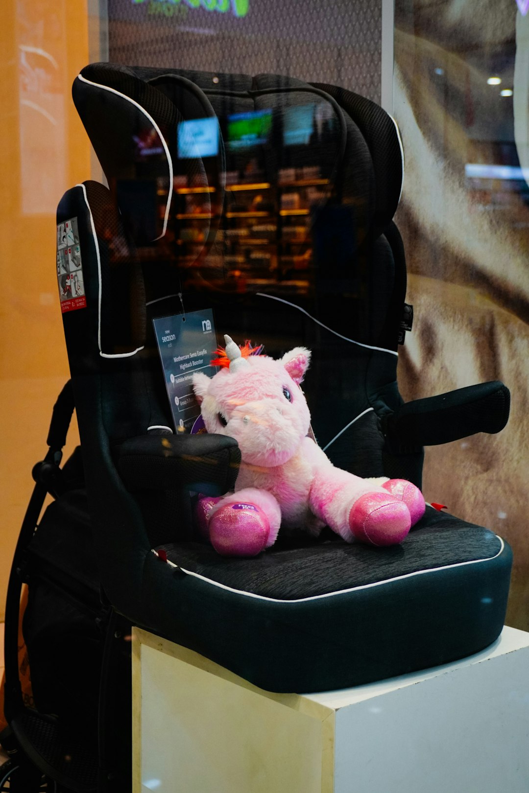 Kindersitz im Auto mit angeschnalltem Kuscheltier